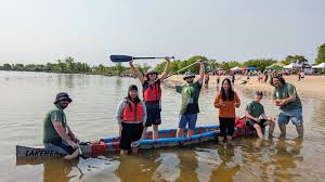 The inaugural Lakehead Concrete Canoe team standing with their canoe at the shoreline